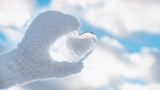 frozen icy heart hand, winter background against clear blue sky and clouds, concept love, romantic, February 14, Valentine's day. festive winter season. Christmas New Year holiday. approach of spring