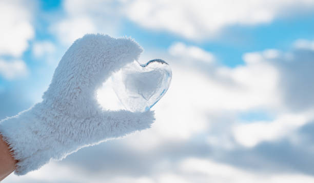 frozen icy heart hand, winter background against clear blue sky and clouds, concept love, romantic, February 14, Valentine's day. stock photo