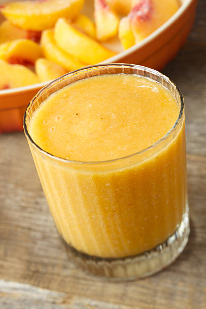 Frozen peach smoothie drink Natural light photo of frozen peach and banana smoothie drink. Selective focus on rear of glass. peach smoothie stock pictures, royalty-free photos & images