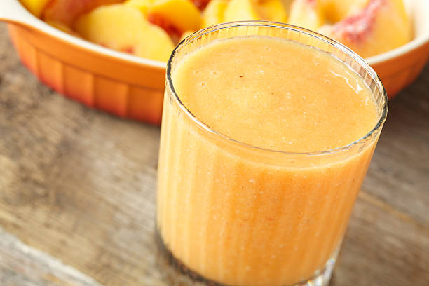 Frozen peach smoothie drink Natural light photo of frozen peach and banana smoothie drink. Selective focus on top of liquid. peach smoothie stock pictures, royalty-free photos & images