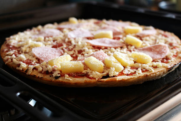 Frozen pizza with ham and pineapple on the plate stock photo
