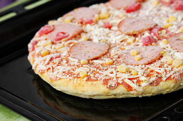 Frozen pizza with salami, cheese, corn and pepper stock photo