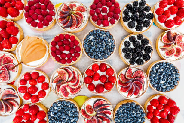 Fruit and Berry tarts dessert assorted top view background Fruit and berry tartlets dessert tray assorted top view background. Beautiful delicious tarts, bright, colorful pastry cakes sweets with fresh raspberries, figs, strawberry. French Bakery pattern. tart dessert photos stock pictures, royalty-free photos & images
