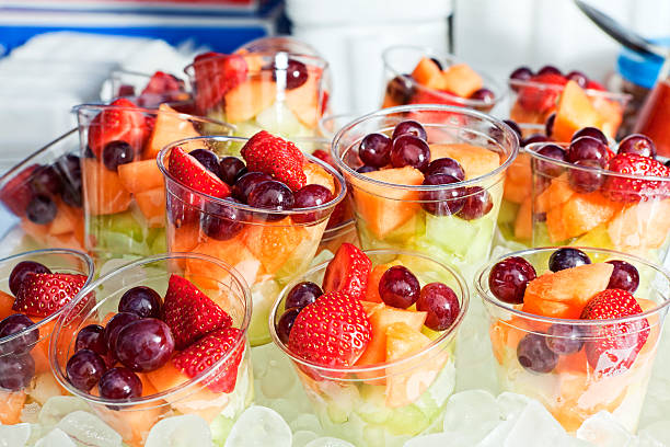 Fruit Cup Strawberries, red grapes, cantaloupe offered in plastic cups on ice at a food fair. fruit salad stock pictures, royalty-free photos & images