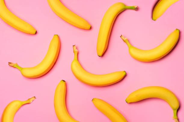 obst-muster von bananen über einem rosa hintergrund - banana stock-fotos und bilder