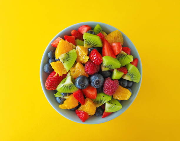 Fruit salad in a bowl on black background (kiwi, orange, strawberry, blueberry) Fruit salad in a bowl made from kiwi, orange, strawberry, blueberry fruit salad stock pictures, royalty-free photos & images