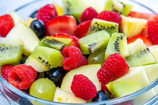 Fruit salad made from various ingredients. Raspberries, strawberries, slices of kiwi, pieces of pear and grapes. Source of vitamins, healthy lifestyle concept.