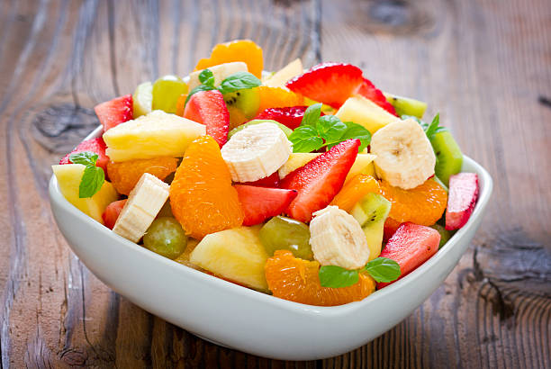 Fruit salad A bowl with fresh, mixed fruit salad on the wooden table fruit salad stock pictures, royalty-free photos & images