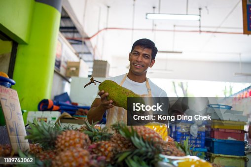istock fruit shop owner holding a jack-fruit examining it , choosing a good quality fruit to his customer 1189763062