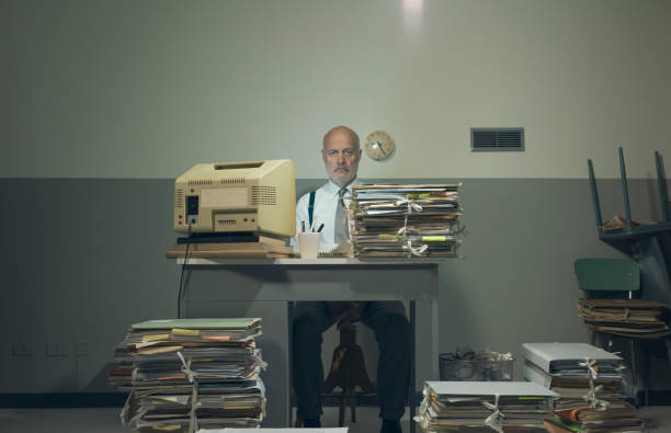 Frustrated businessman overloaded with paperwork Frustrated vintage style businessman working in a rundown old office space, he is overloaded with papework bureaucracy stock pictures, royalty-free photos & images