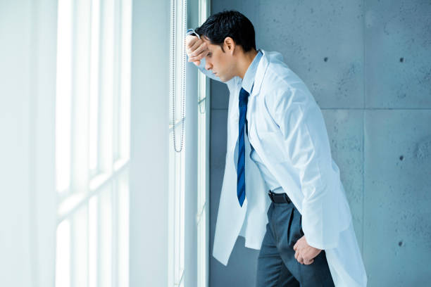 Frustrated doctor leaning on window stock photo