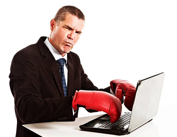 Frustrated grumpy businessman in boxing gloves cannot type on laptop