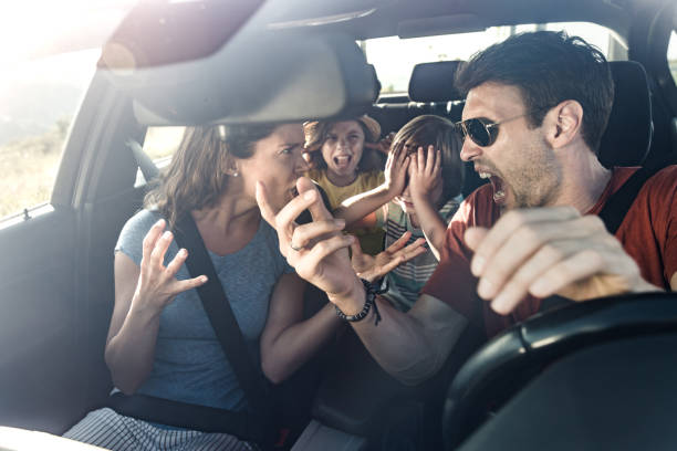 Frustrated parents arguing during trip by a car. Angry parents arguing while traveling with their displeased kids in car. The view is through windshield. fighting stock pictures, royalty-free photos & images