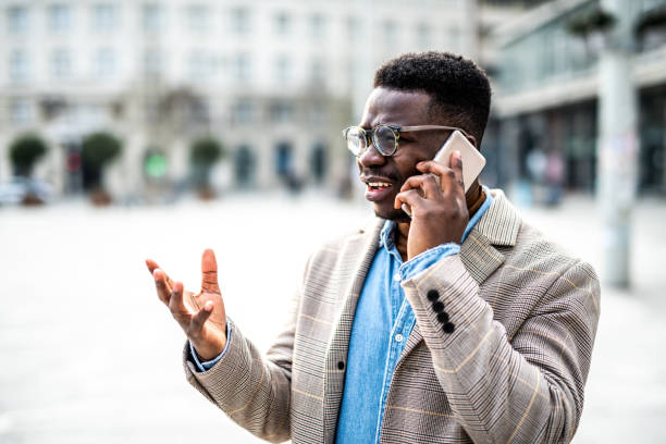 Frustrated young man talking on phone in the city. stock photo