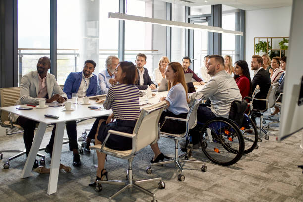 Full Complement of Executives at Management Meeting Comprehensive viewpoint of diverse group of business executives sitting together at conference table and looking at camera. organized group stock pictures, royalty-free photos & images