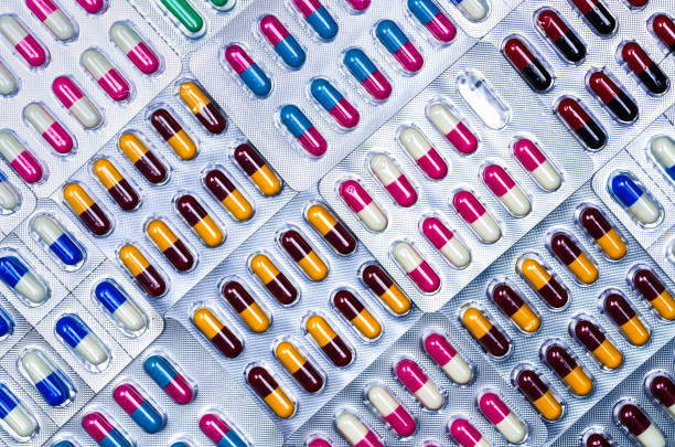 Full frame of colorful antimicrobial capsule pills. Quality control error in pharmaceutical manufacturing. Blister pack missing one capsule of antibiotic pill. Drug resistance. Defective concept. Full frame of colorful antimicrobial capsule pills. Quality control error in pharmaceutical manufacturing. Blister pack missing one capsule of antibiotic pill. Drug resistance. Defective concept. pics for amoxicillin stock pictures, royalty-free photos & images