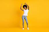 Full length body size photo of young female student with black skin listening, music dancing with headphones wearing casual clothes smiling isolated on bright yellow color background