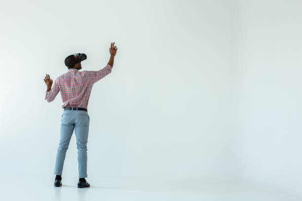 Full length of a pleasant afro american man in VR glasses Immensive device. Full length of a professional afro american man standing against white background while wearing VR glasses virtual reality point of view stock pictures, royalty-free photos & images