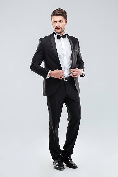 full length of handsome young man in tuxedo with bowtie - smoking stockfoto's en -beelden