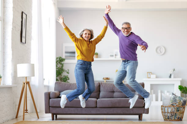 Full length of happy active energetic senior caucasian family couple jumping and having fun together stock photo