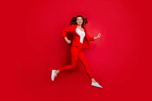 Volledige lengte foto van vrolijke meisje loopt met heldere lippen stok geïsoleerd over rode achtergrond​​​ foto