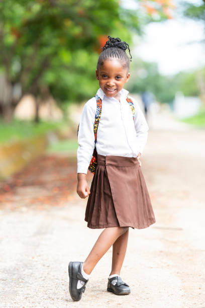 Full length portrait of young African schoolgirl on rural road stock photo