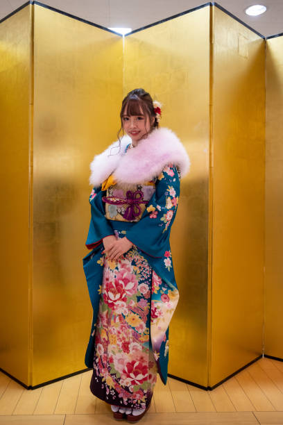 Full length portrait of young woman in ‘Furisode’ kimono with fur neck stole standing in front of golden ‘Byobu’ folding screen for ‘Seijin Shiki’ coming-of-age ceremony Full length portrait of young woman in ‘Furisode’ kimono with fur neck stole standing in front of golden ‘Byobu’ folding screen for ‘Seijin Shiki’ coming-of-age ceremony furisode stock pictures, royalty-free photos & images
