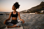 istock Full length shot of an attractive young woman practicing yoga on the beach at sunset 1317514465