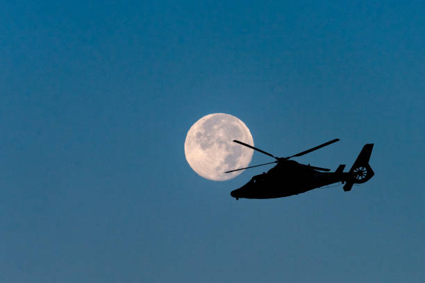 Full Moon and Helicopter Silhouette A Coast Guard helicopter is silhouetted as it flies past a full moon in a composite image. public service stock pictures, royalty-free photos & images
