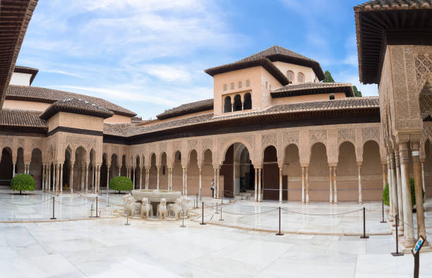 Full panoramic exterior view at the Patio at the Lions, twelve marble lions fountain on Palace of the Lions or Harem, Alhambra citadel, tourist people visiting stock photo