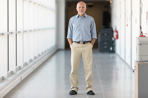 full-length portrait of a man standing in the hallway inside a modern new building
