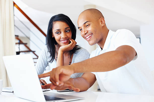 Fun on the internet Portrait of young beautiful couple having a good time in front of their laptop in front of stock pictures, royalty-free photos & images