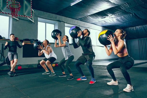 functional fitness workout at the gym with medicine ball Functional fitness workout at the gym with medicine ball. The group of young people during training session. Fit athletic men and women at health club. Healthy lifestyle concept earth's core stock pictures, royalty-free photos & images