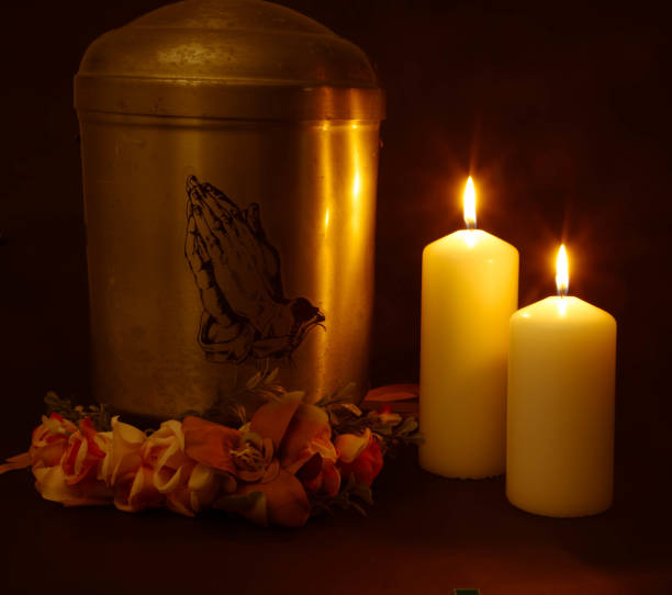 Funeral urn with praying hands and burning candles. stock photo