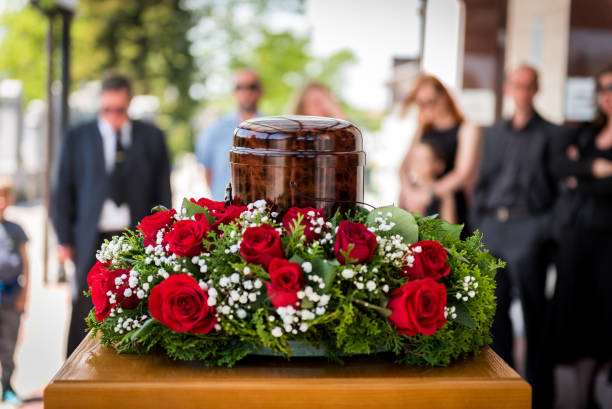 Funerary urn with ashes of dead and flowers at funeral. stock photo
