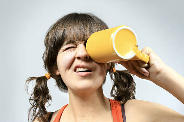 funny girl with tails looks into a large yellow mug stock photo