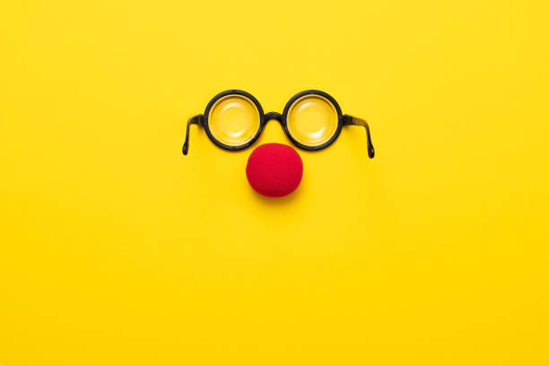 Funny glasses, red clown nose and tie lie on a colored background, like a face. Funny glasses, a red clown nose and tie on a colored background, like a face. Flat lay. Funny costume for the holidays. Anonymous concept. clown's nose stock pictures, royalty-free photos & images
