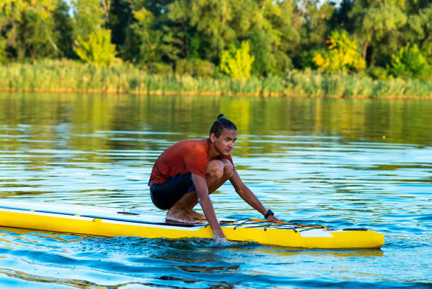 Funny guy, teenager paddling on a SUP board on large river stock photo