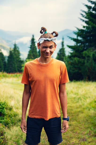 Funny guy teenager stands on the mountain meadow stock photo