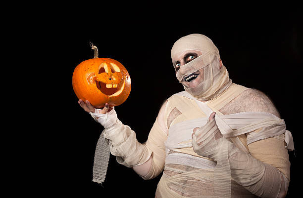 funny halloween mummy with smiling pumpkin - kostuum stockfoto's en -beelden