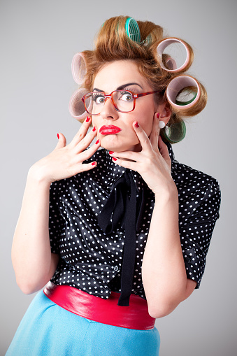 Funny nerdy housewife with curlers in hair wearing glasses posing