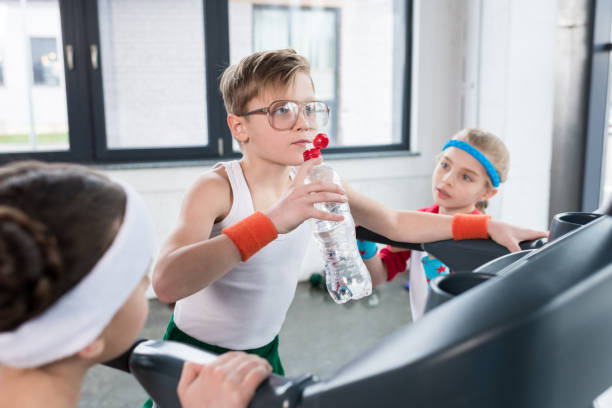 funny kids in sportswear training on treadmill at gym together,...