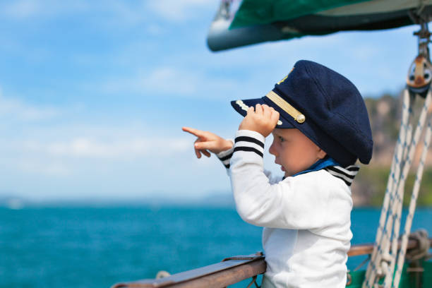 Funny little baby captain on board of sailing yacht stock photo