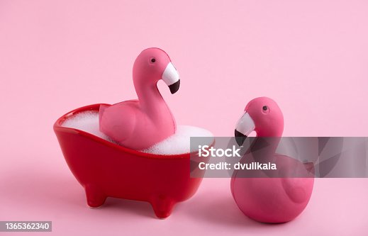 istock Funny pink flamingoes and  bath with foam on a pink background. 1365362340