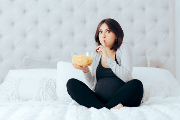 Funny Pregnant Woman Eating Potato Chips in Secret stock photo