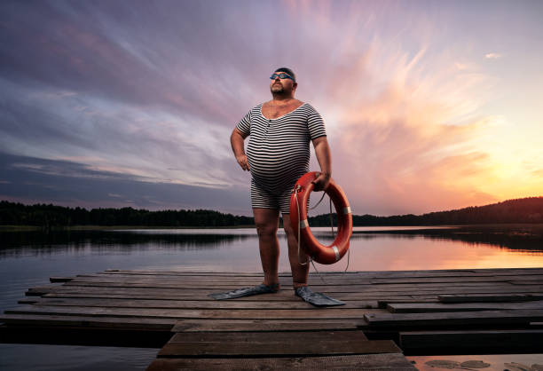 Funny retro swimmer Fuunny overweight, retro swimmer by the lake, at the sunset with copy space stomach photos stock pictures, royalty-free photos & images
