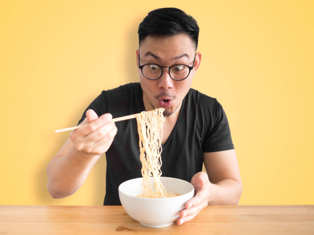 Funny surprised face man eatting instant noodles. stock photo