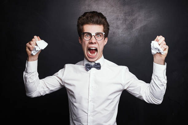Furious male student with crumpled paper in hands stock photo