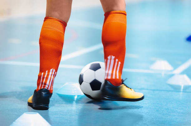 futsal league. indoor soccer player in futsal shoes training dribble drill with ball. indoor soccer training. running futsal player, soccer ball, white cones. indoor football player with classic ball. - futsal imagens e fotografias de stock