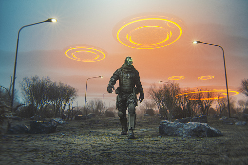 Futuristic cyborg walking in desert with flying UFOs.